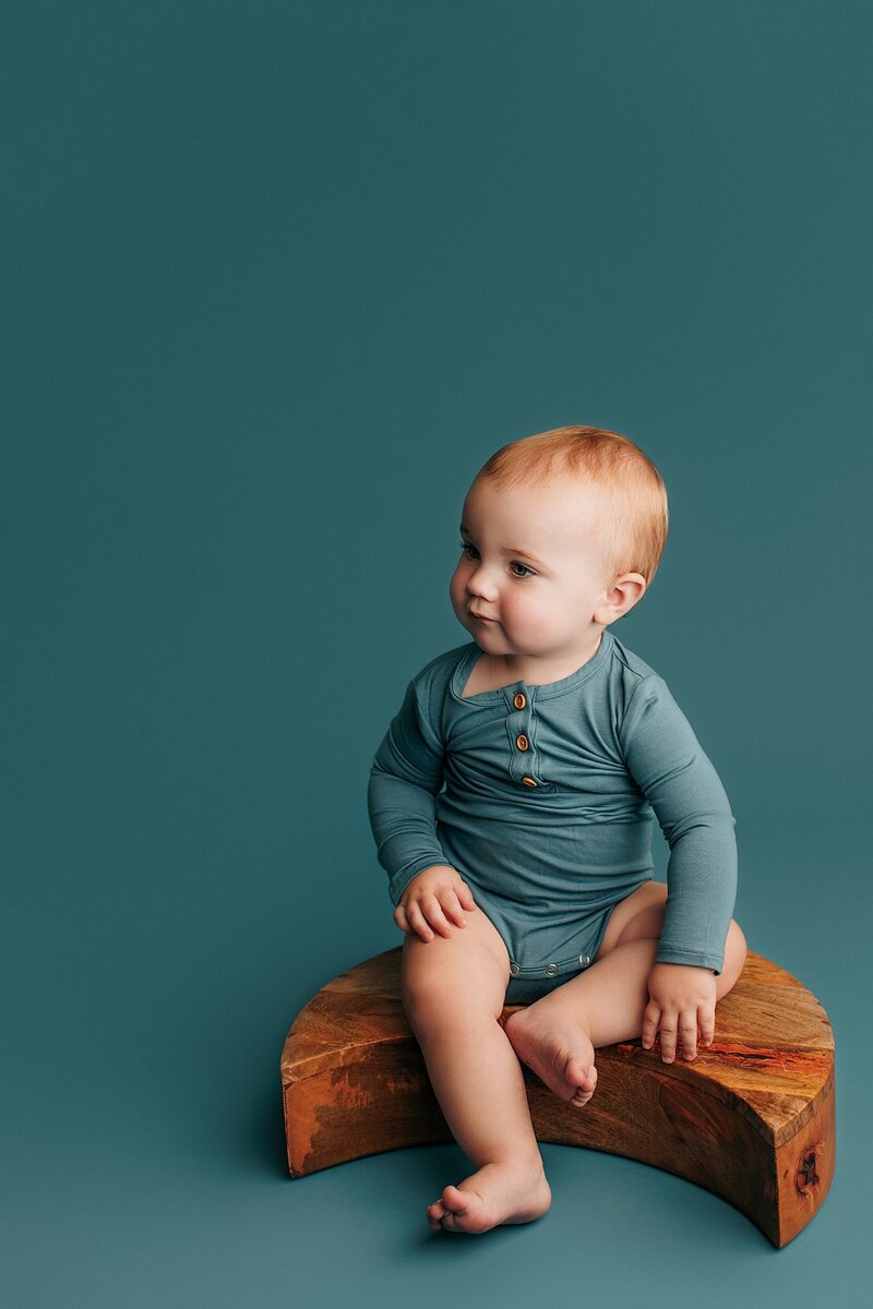 Curious baby raising eyebrows with big smile during milestone shoot