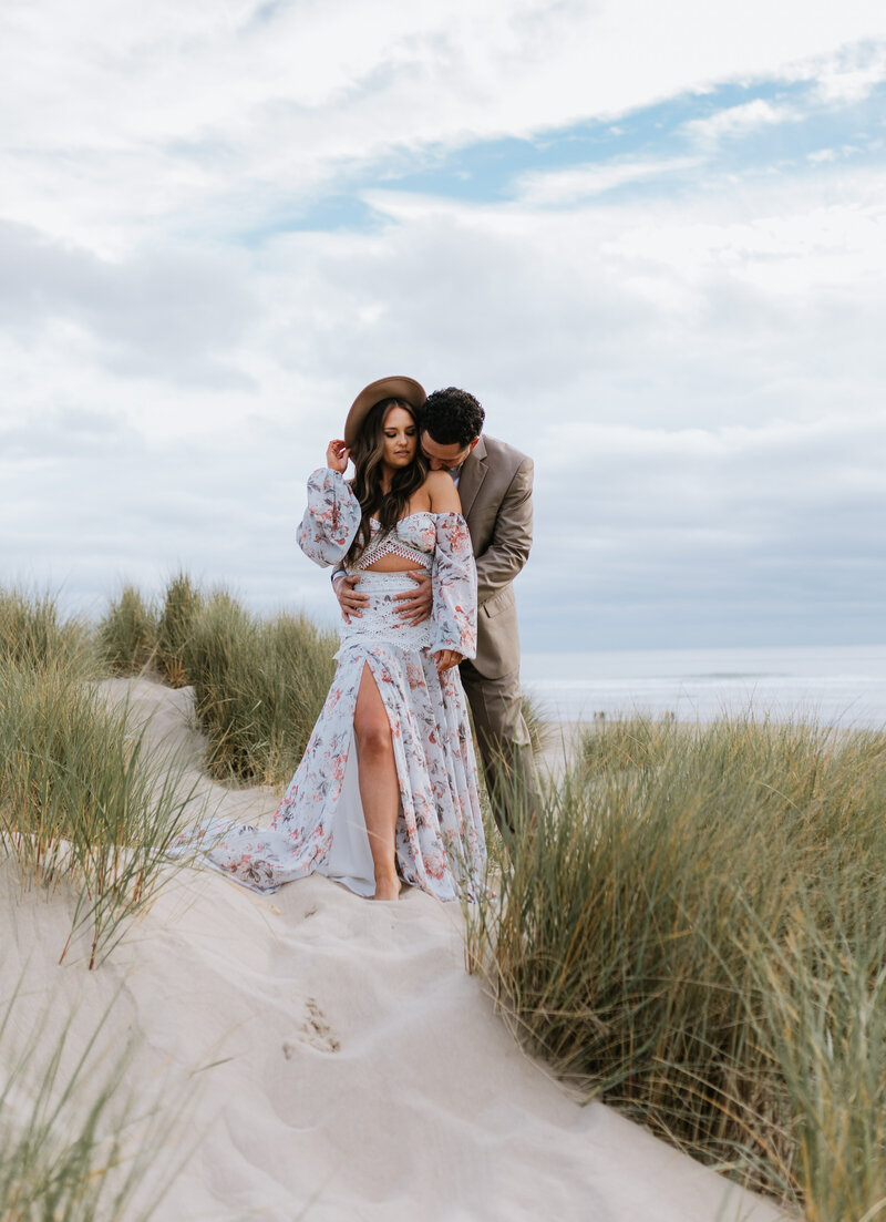 Bride and groom embracing in an open field with tall grass, showcasing natural romance captured by an Oregon Coast Elopement and Wedding Photographer.