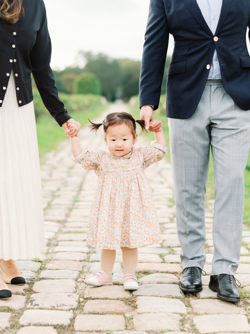 Elegant Couple walking in the garden of the chateau smith haut lafitte with their little girl