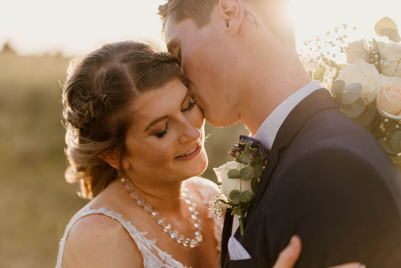 Bride and groom embrace in a grassy field while the sun sets - Brisbane elopement photographer