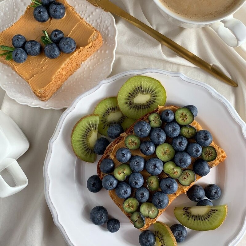 Plate of toast with nut butter, berries, and kiwi.