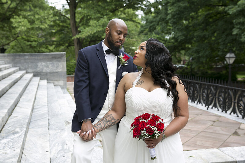 Bride and groom on the steps of the Second National Bank of Philadelphia PA with red roses