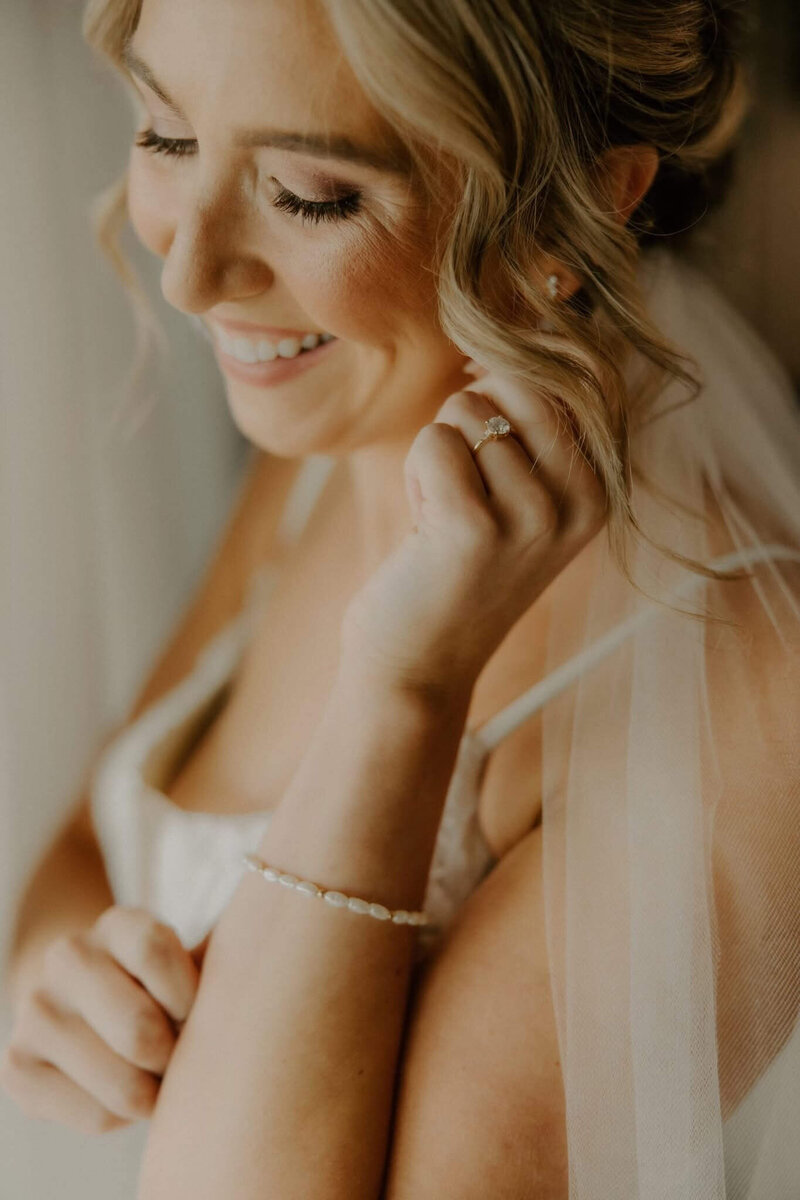 stunning bride laughing and glancing down as she soaks in her bridal makeup look with Stephanie Schuh Beauty