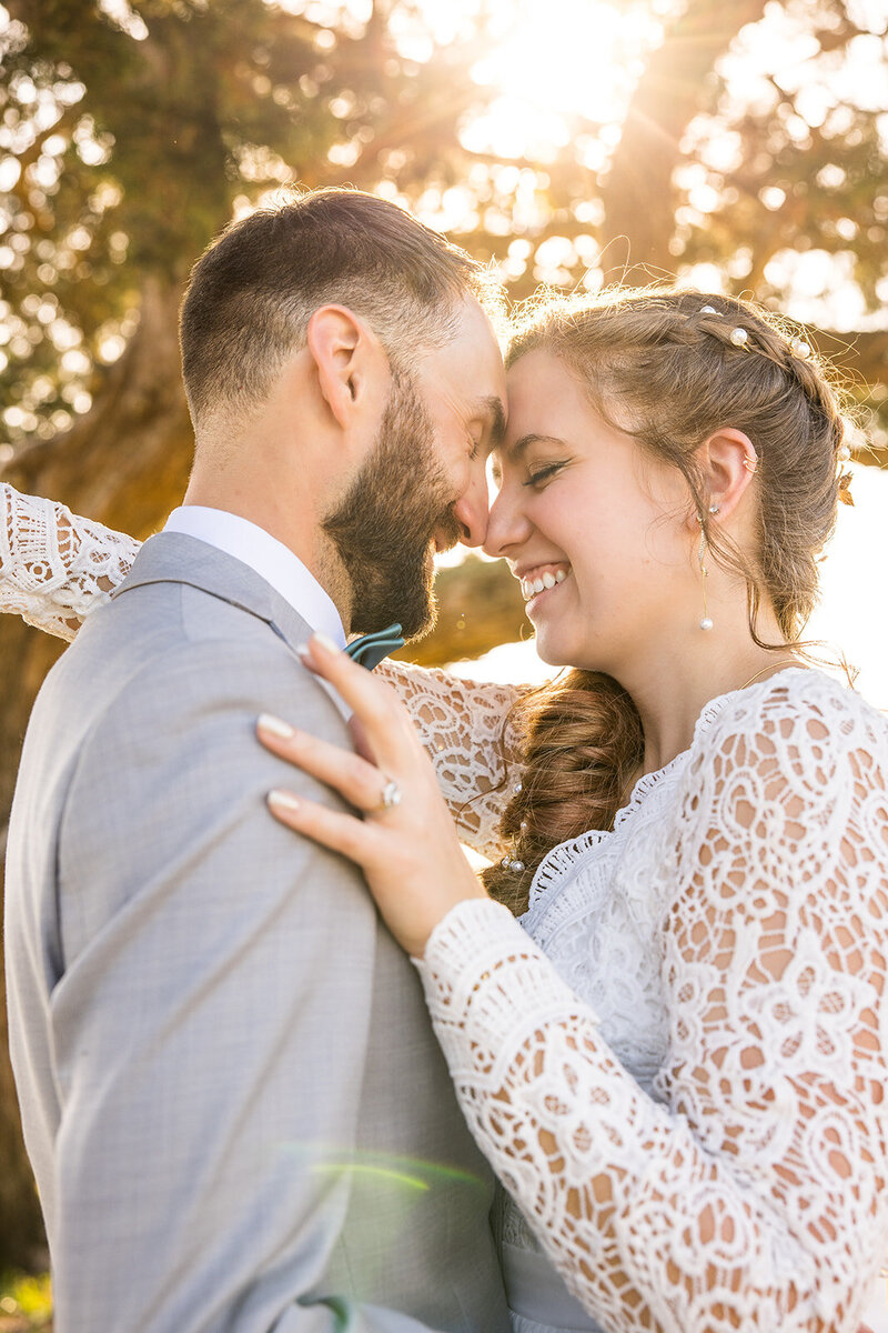 Bride and groom embrace under warm golden hour light.