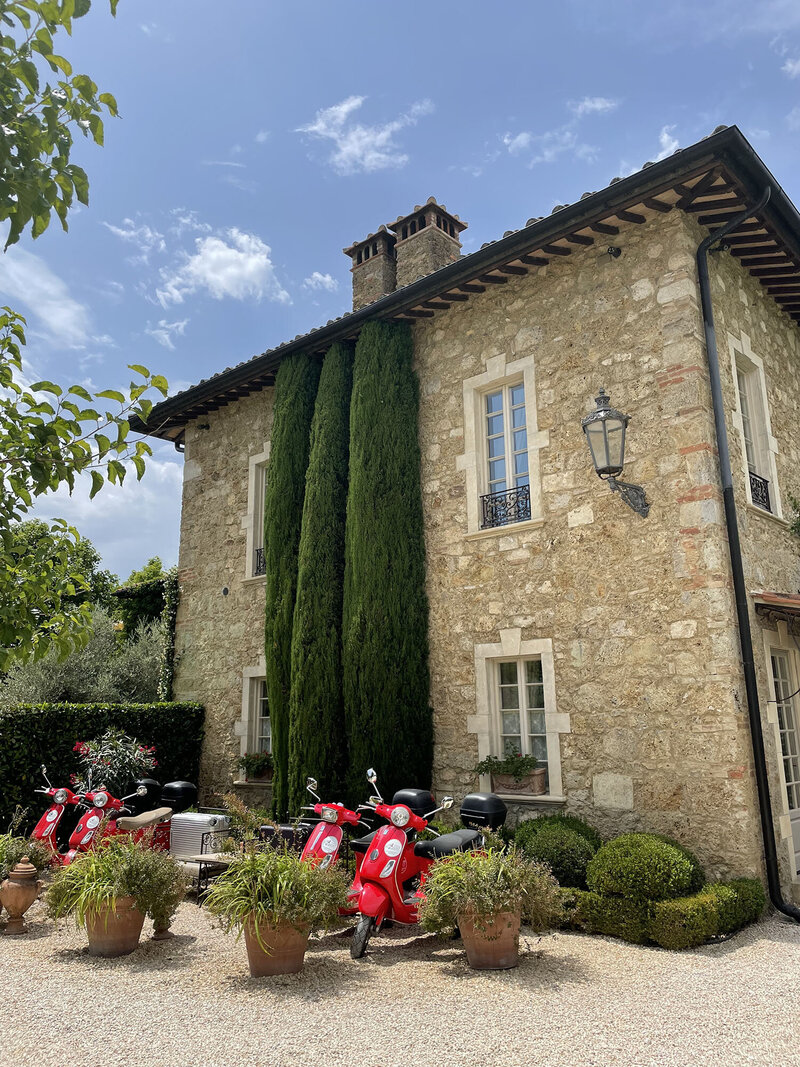 classic Italian stone building with olive trees and gravel pathway