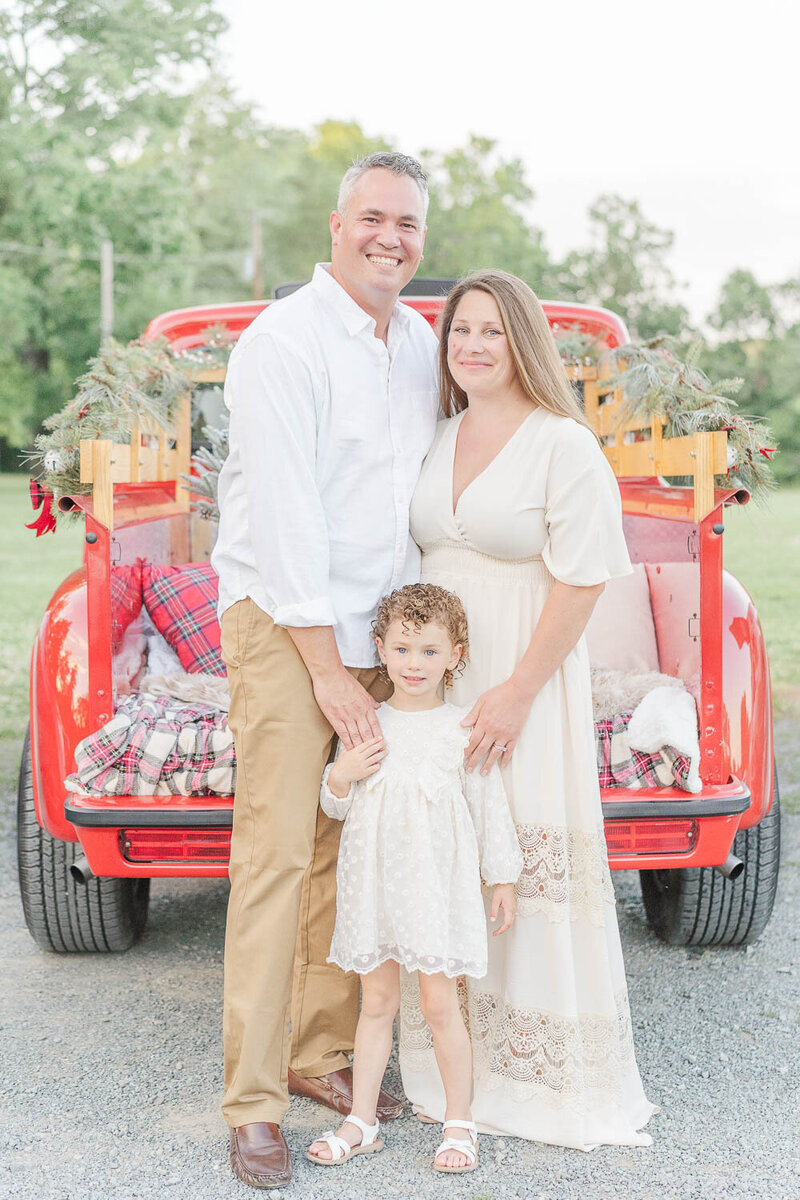 family of 3 standing posing for photos during red truck minis in Fairfax County, VA