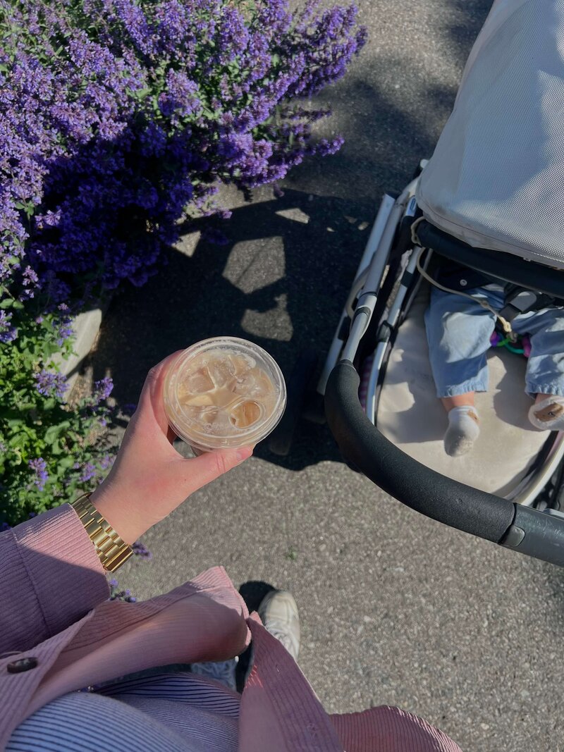 mom holding coffee walking with baby