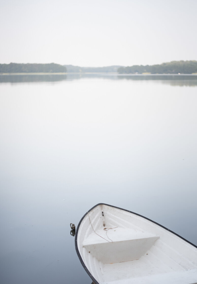 A tranquil white boat floating on a calm lake surrounded by nature, symbolizing serenity, holistic wellness, and a peaceful connection to the outdoors.