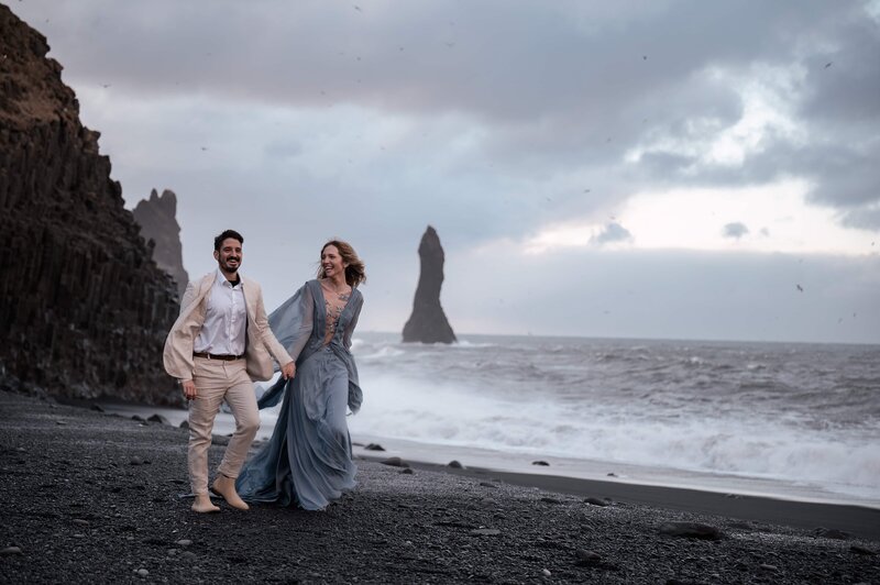 Bride in windswept gown on black sand beach during Iceland elopement