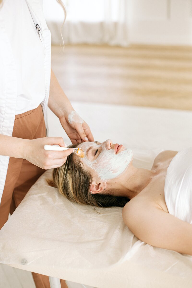 Woman is receiving a facial with a brush and has her eyes closedd