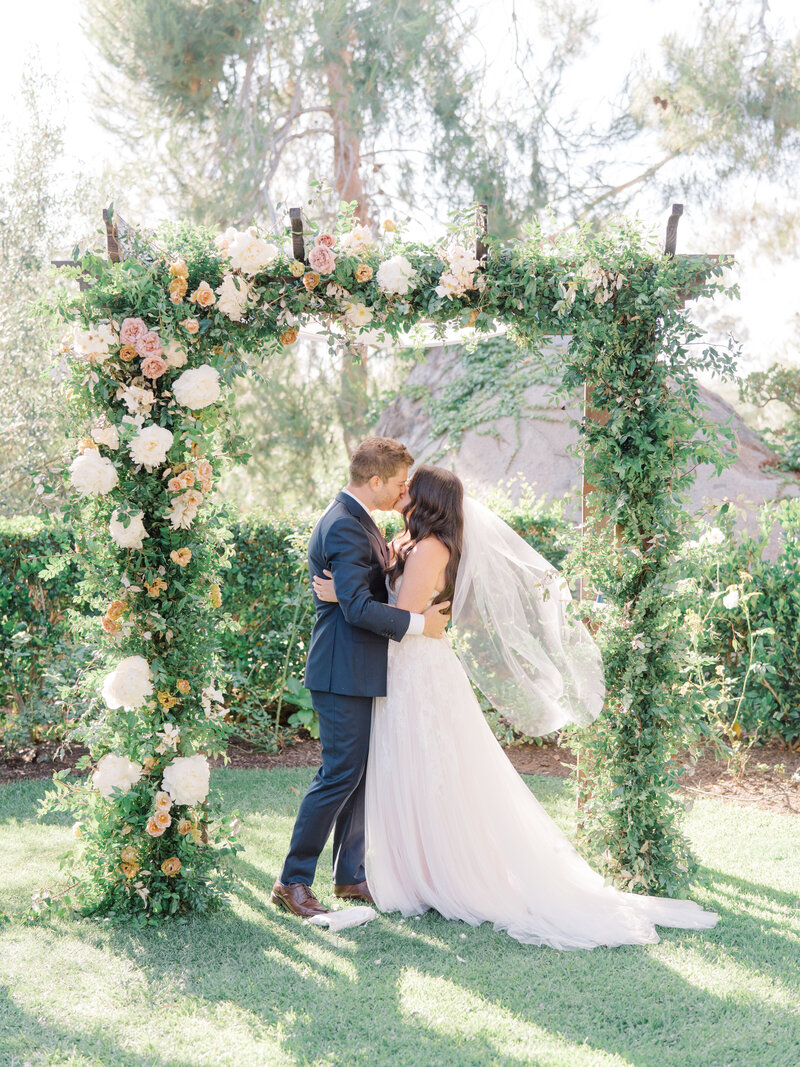 bride and groom kissing under an arbor