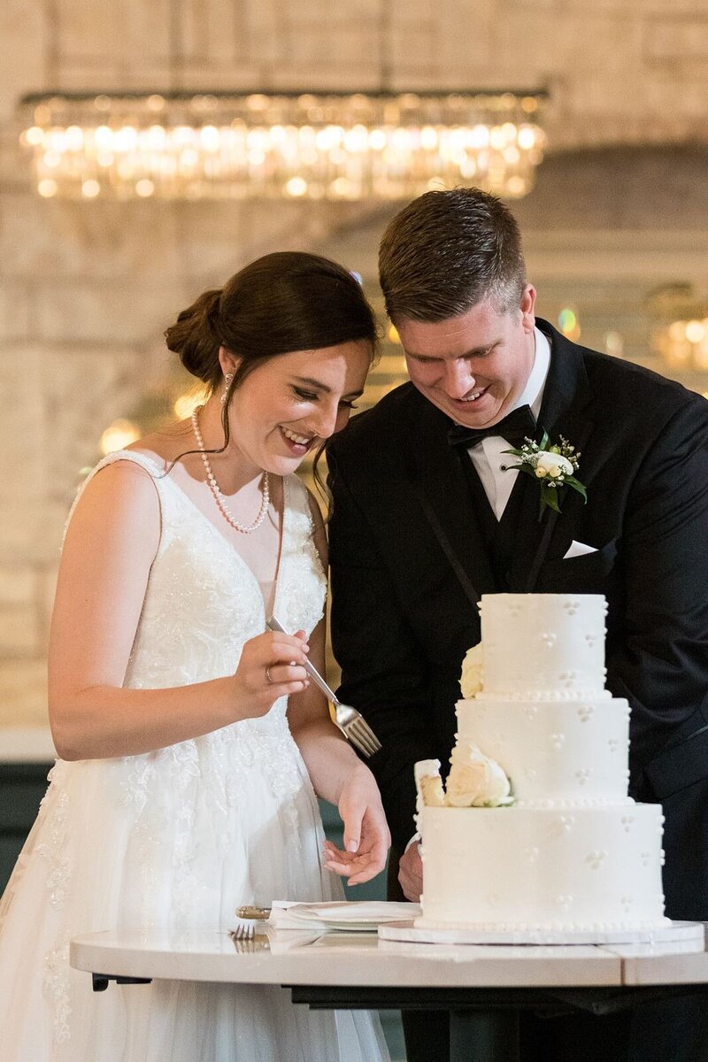 bride and groom cutting cake under glowing chandelier lights