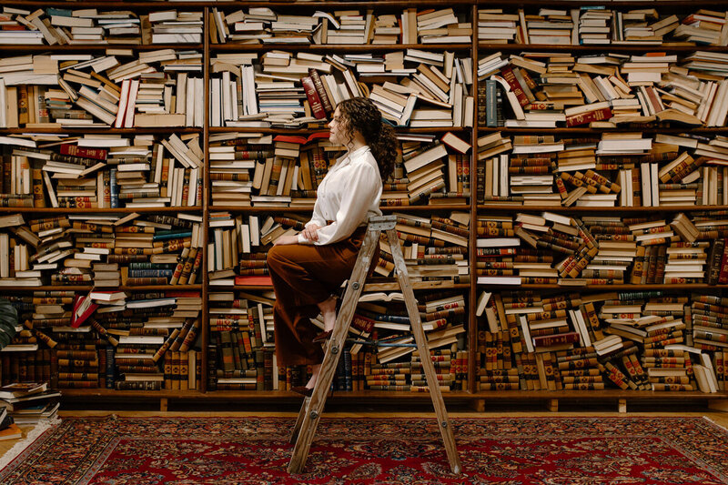 woman sitting on a ladder in a library