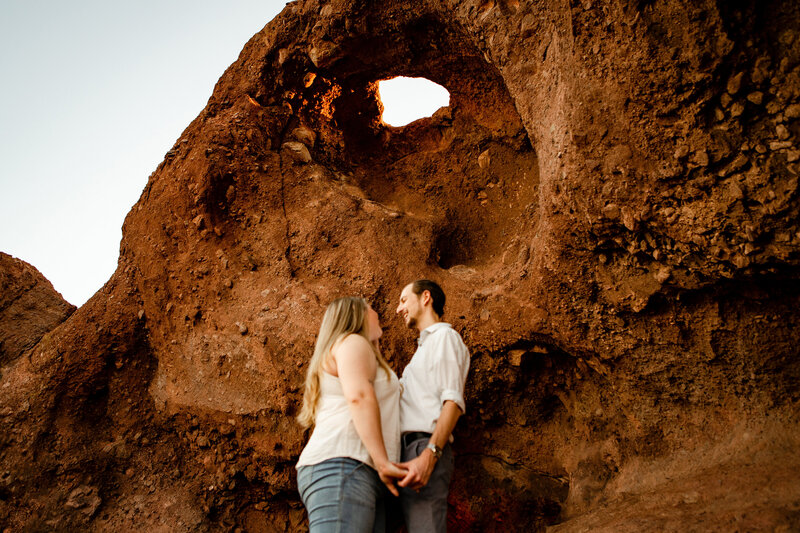 Papago Park engagement photo shoot couple standing under red rocks in Phoenix, Arizona