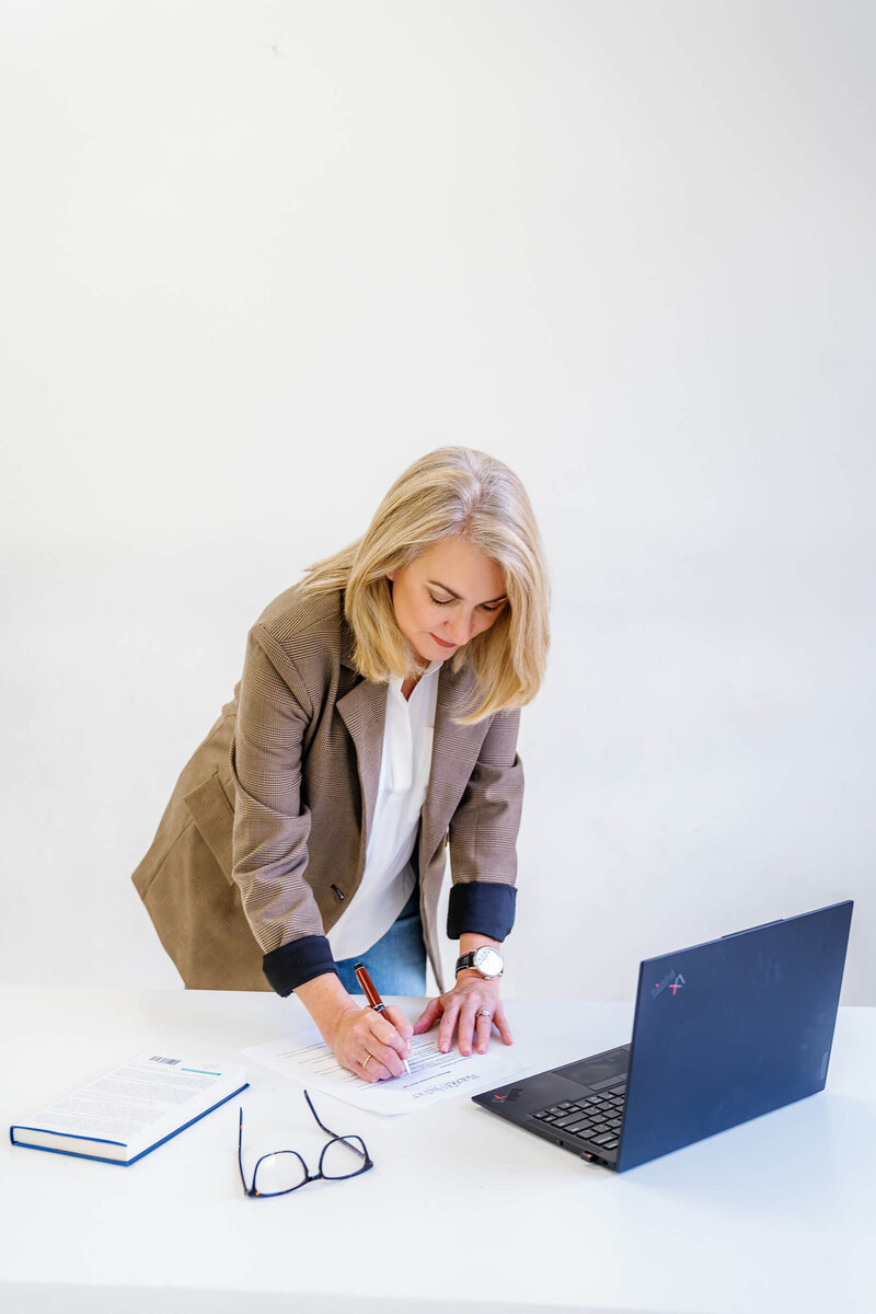 Melissa Greenwell, working, at her desk, writing down leadserhip training notes