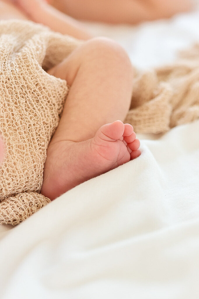 Close-up of tiny baby foot capturing delicate newborn details in soft natural light. Lifestyle photography by Sophie Louise.