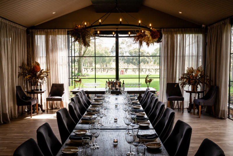 A wedding reception table set up with a window in the background opening out to gardens.  