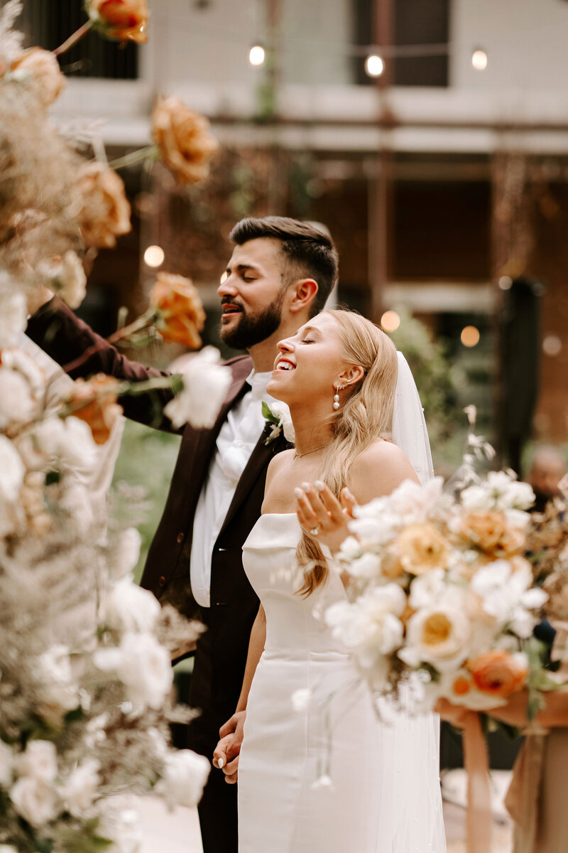 Kelly and Michael Lugo holding hands, smiling and singing praises with closed eyes at their wedding ceremony