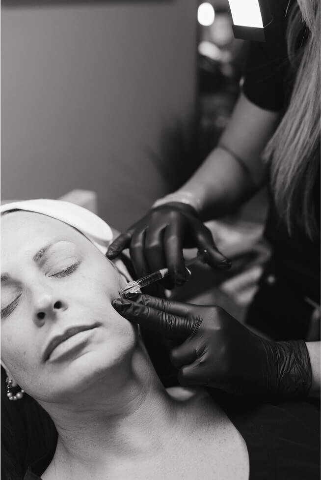 A black and white photo of a woman receiving aesthetic injections. 