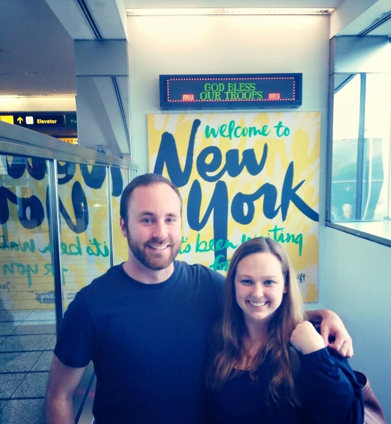 couple in front of welcome to new york sign