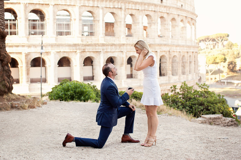 A man on bended knee proposing in front of the Colosseum. Taken by Rome Surprise Proposal Photographer, Tricia Anne Photography