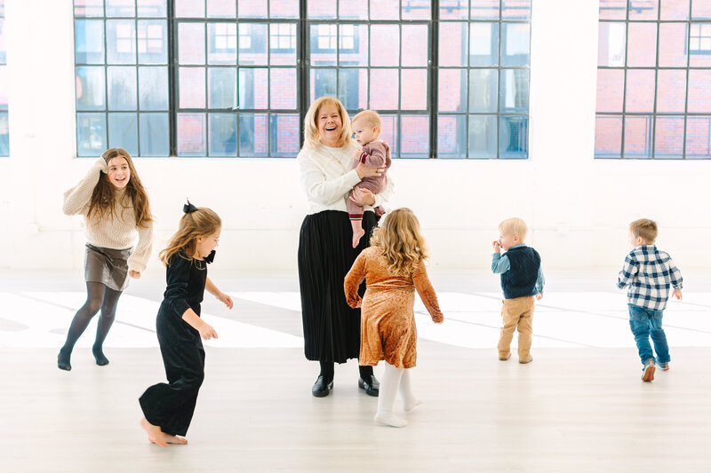 Grandma holding baby while other kids run around her