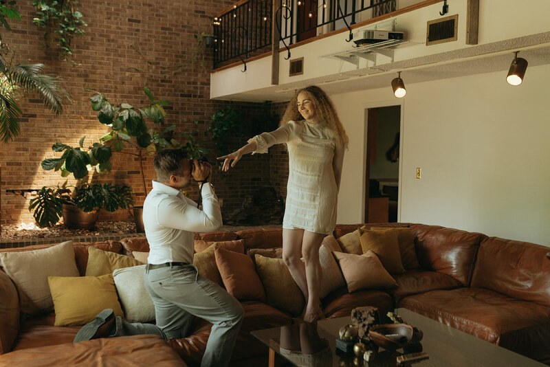 man taking picture of woman on a couch during at home couples photos, captured by Elsie Goodman, an NYC couples photographer