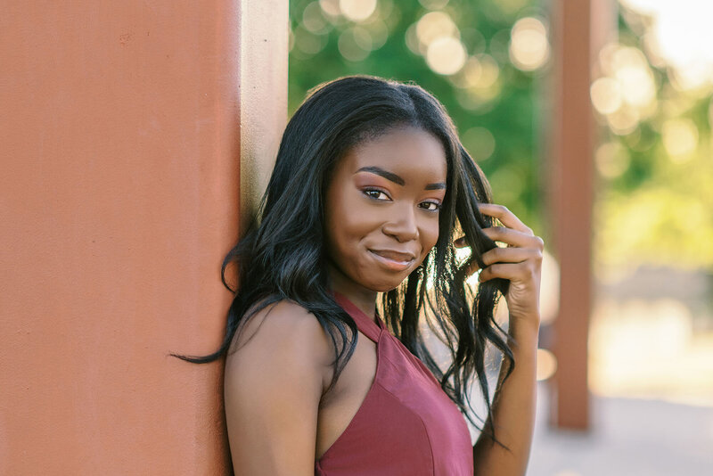 Girl wearing red dress leaning against a pillar for her 8th grade graduation photos