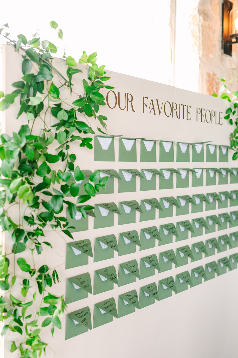 Creative wedding seating chart display with green envelopes and modern calligraphy, designed by Eventive Designs for a stylish Austin celebration.