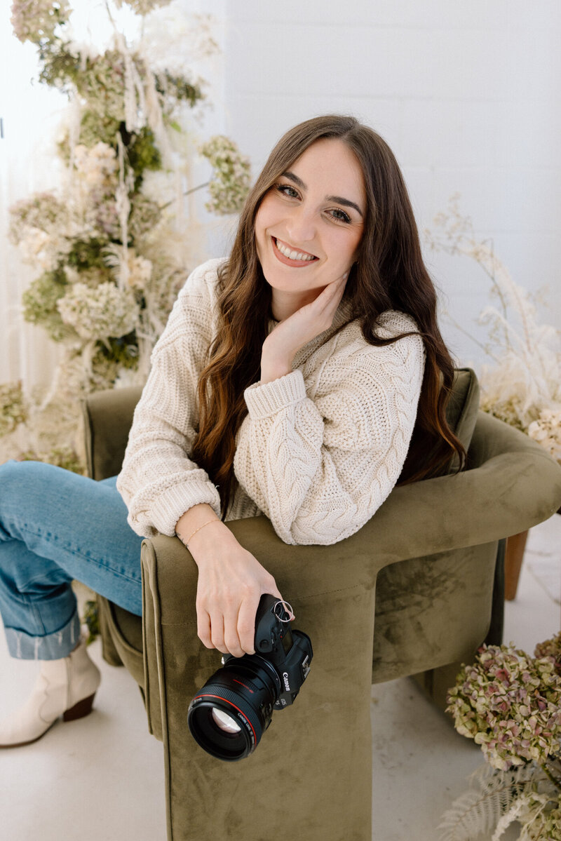 A tulsa wedding photographer sitting in a chair with her camera.