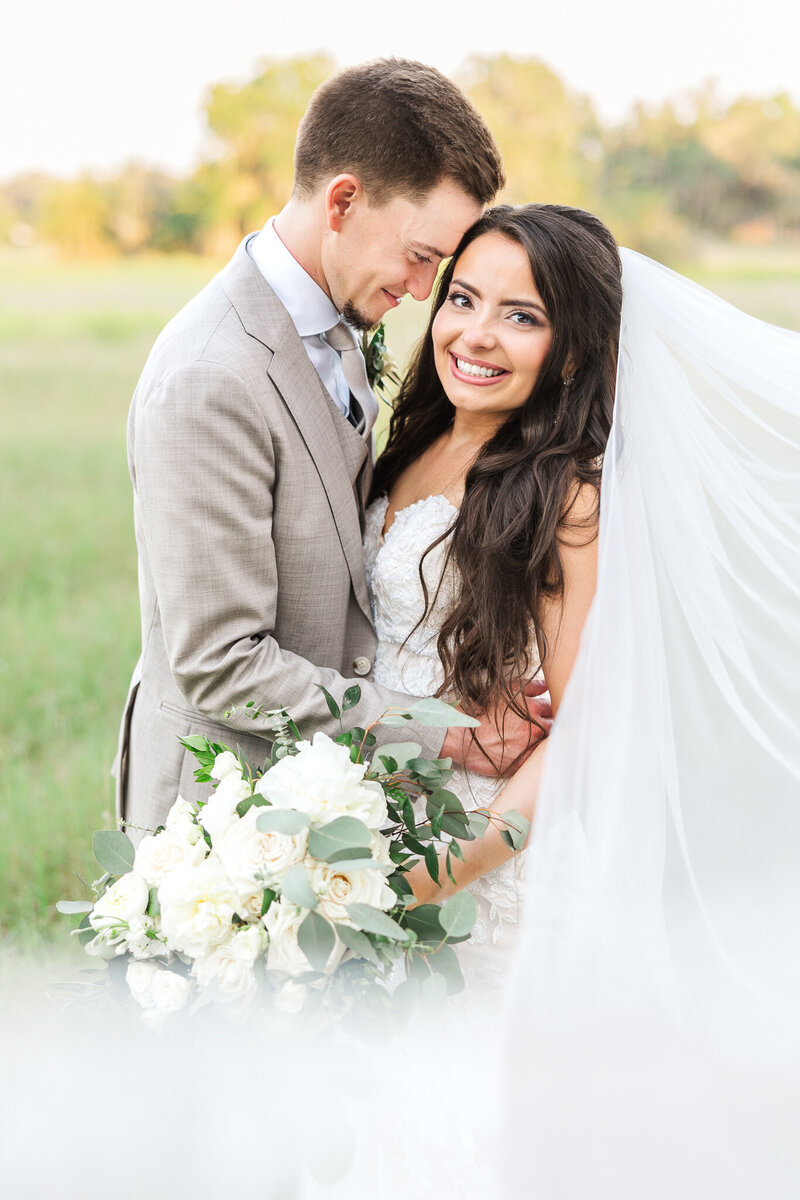 bride smiles at camera while holding green and white bouquet