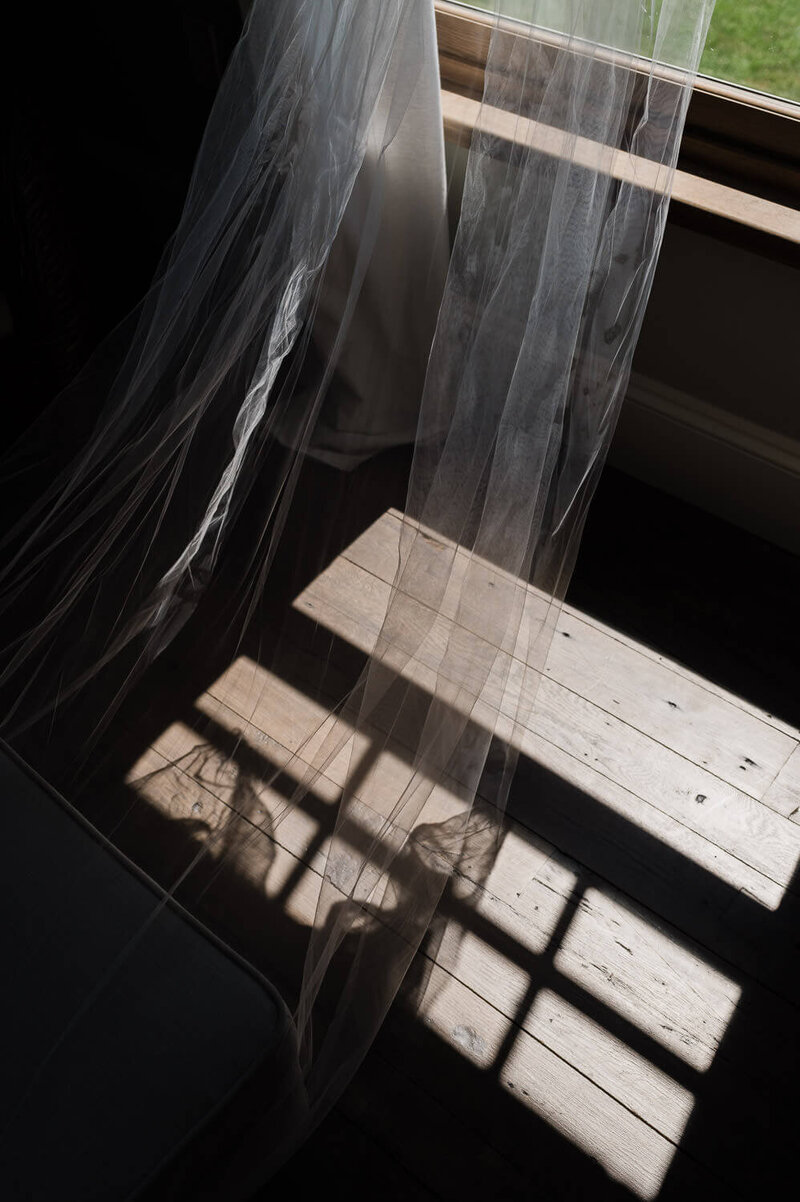 Photo of a veil hanging near window with the sun shining in