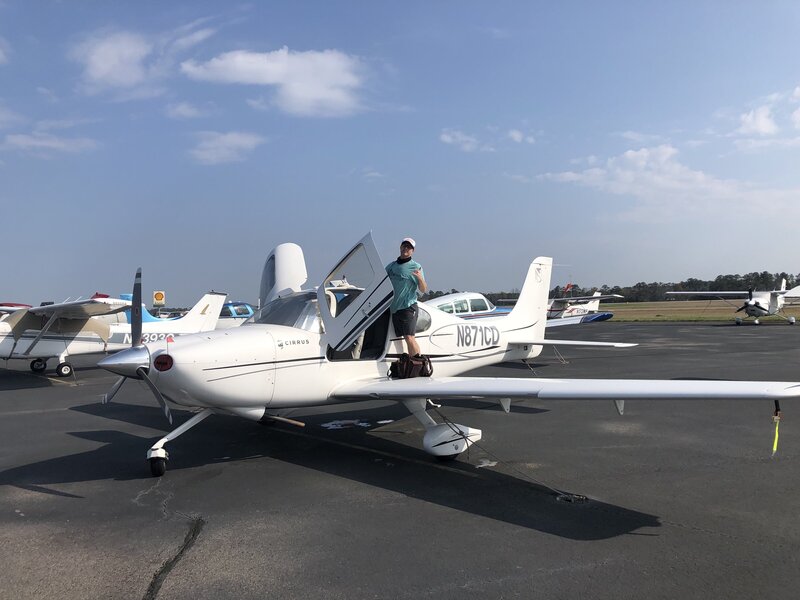 Wilmington and Bald head island wedding photographer Eric Boneske stands with camera in front of airplane.