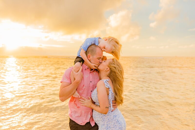 lahaina family portrait featuring family of three snuggling at the beach photographed by love and water