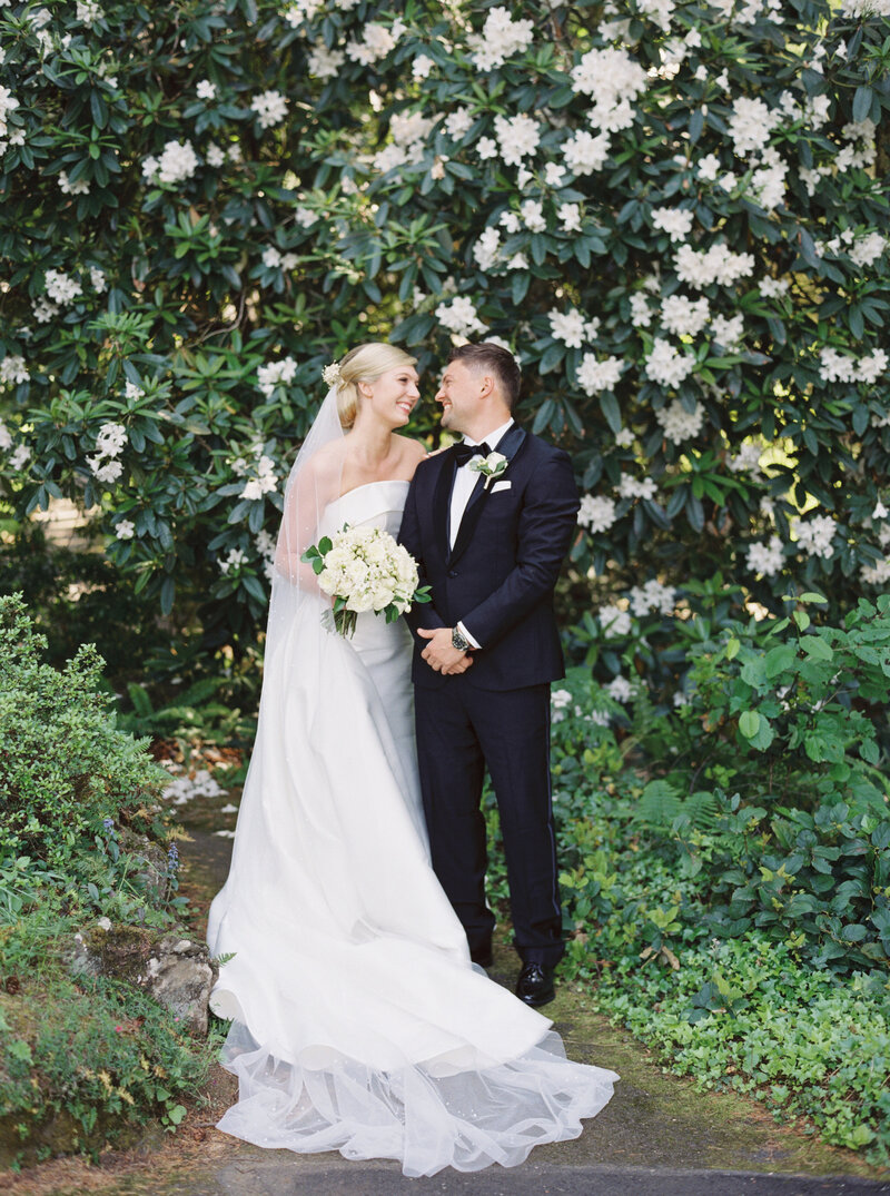modern bride and groom posed next to a large rhododendron plant