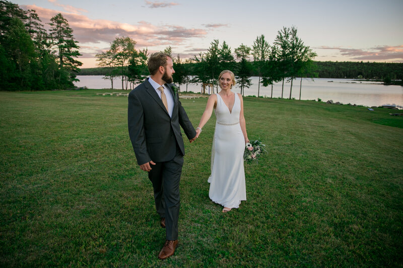 Bride and groom holding hands while walking with lake in back | Wedding Photography Harmony, Maine
