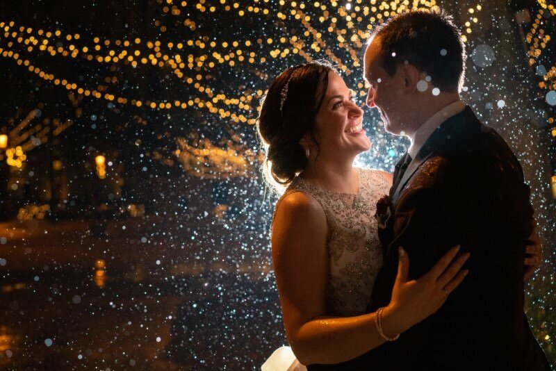 bride looks at her groom on their wedding day as soft rain falls during the nights of lights in st augustine florida