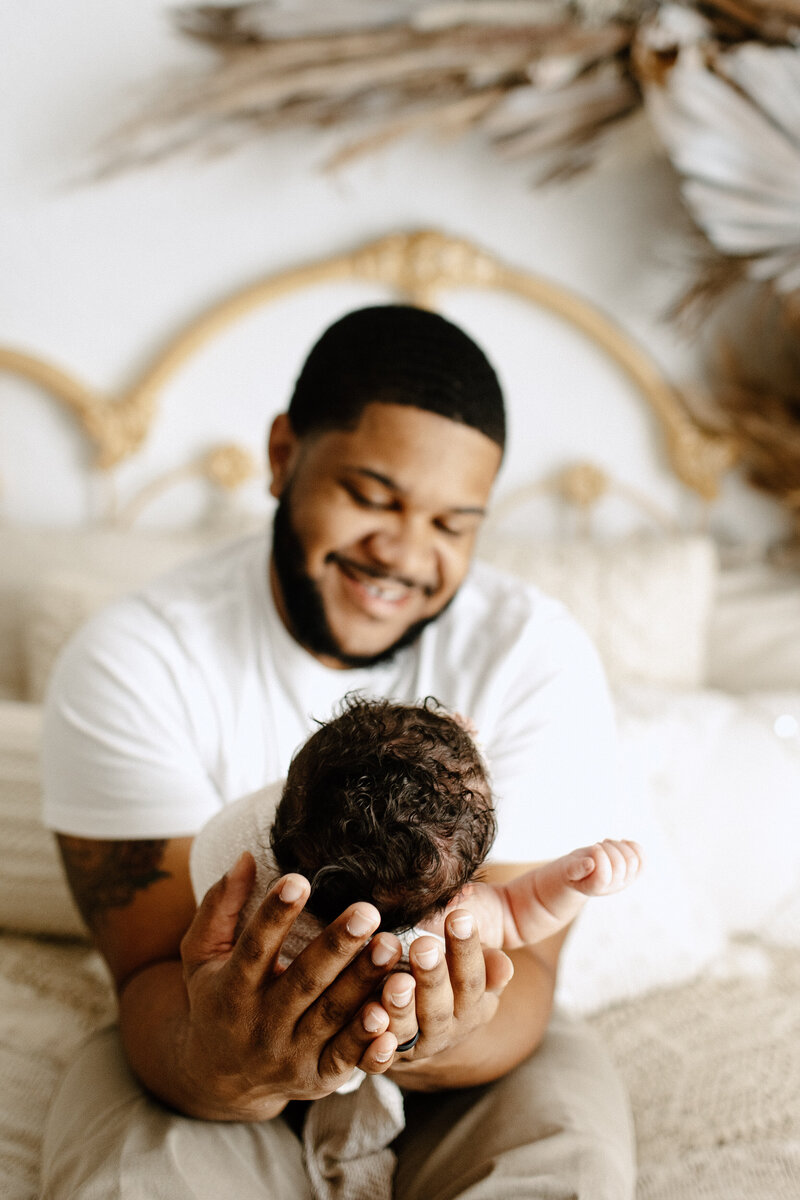 Newborn photography family photo man in white shirt holding baby and smiling in Tampa, Florida Nadine B Photography