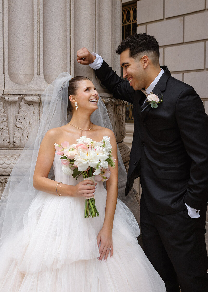 bride looking at groom in front of a column