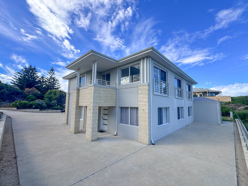 Exterior of a two story home in grey with cream block and concrete surrounding area in Rockingham