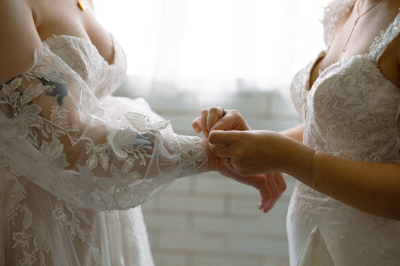 A person helping their partner put on a bracelet on their wedding day 