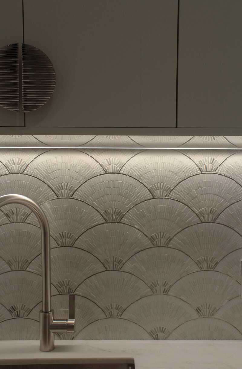 Close up of modern laundry room with mosaic backsplash, textured handles and white cabinetry by Sister Studio.