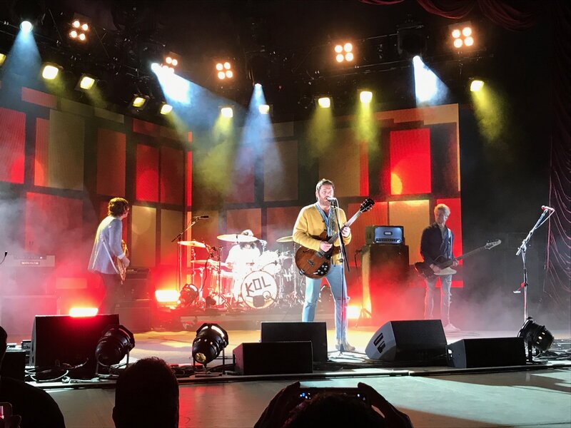 Alternative Rock Band, Kings of Leon, performing on stage in front of yellow and red lighting
