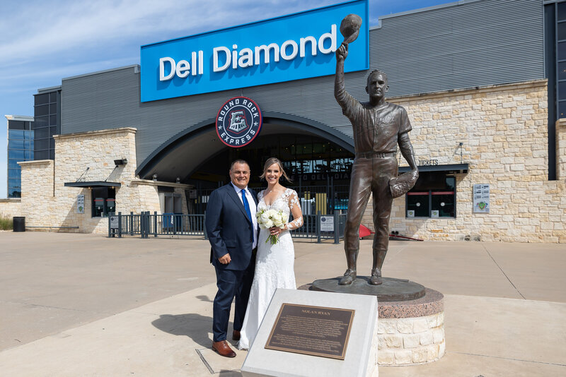 bride and groom pose by baseball stadium