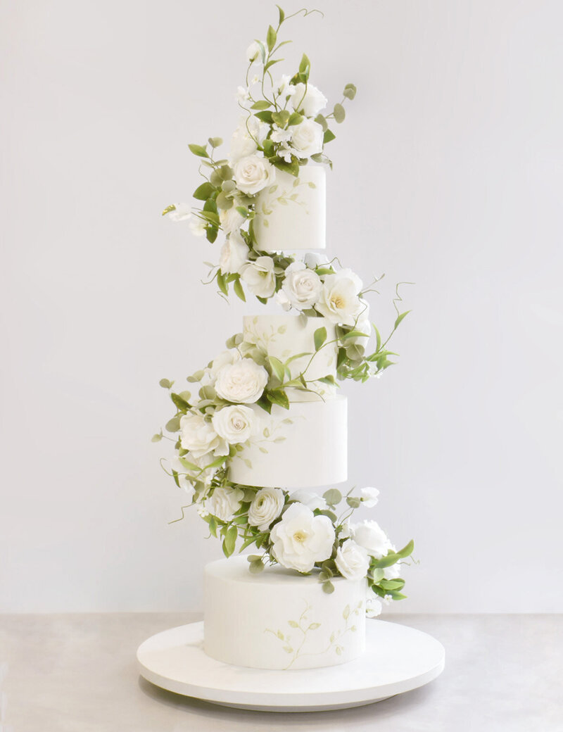 White wedding cake with delicate gold edges and a sugar flower arrangement