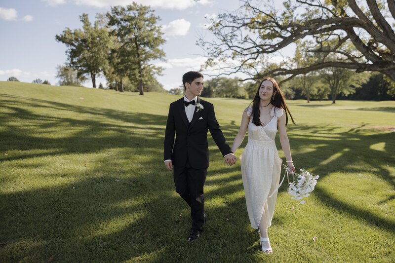 bride and groom walking in grass towards camera