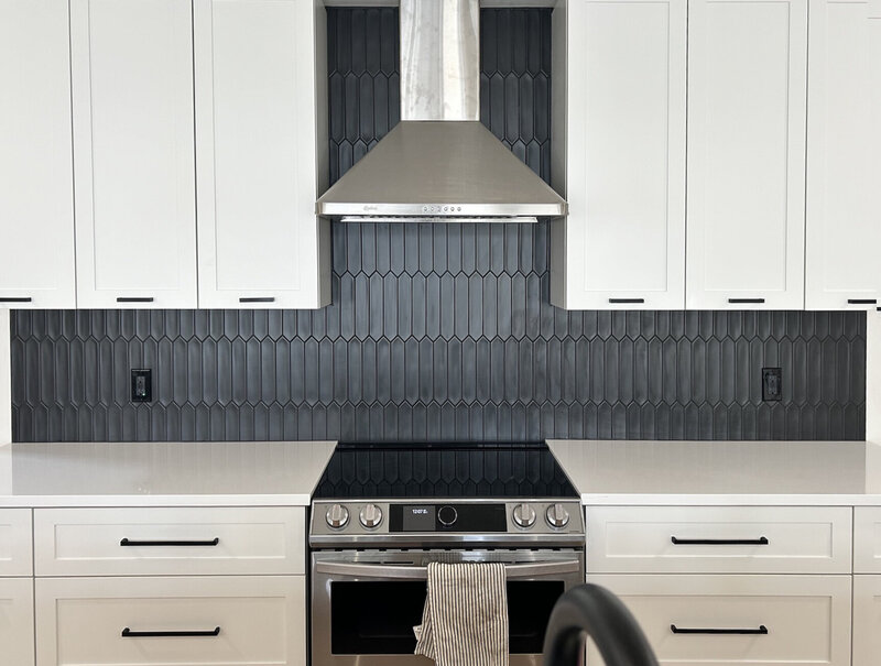 White kitchen cupboards with skinny grey vertical backsplash tiles and black