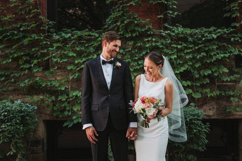 Portrait of bride and groom standing next to each other near an ivy wall