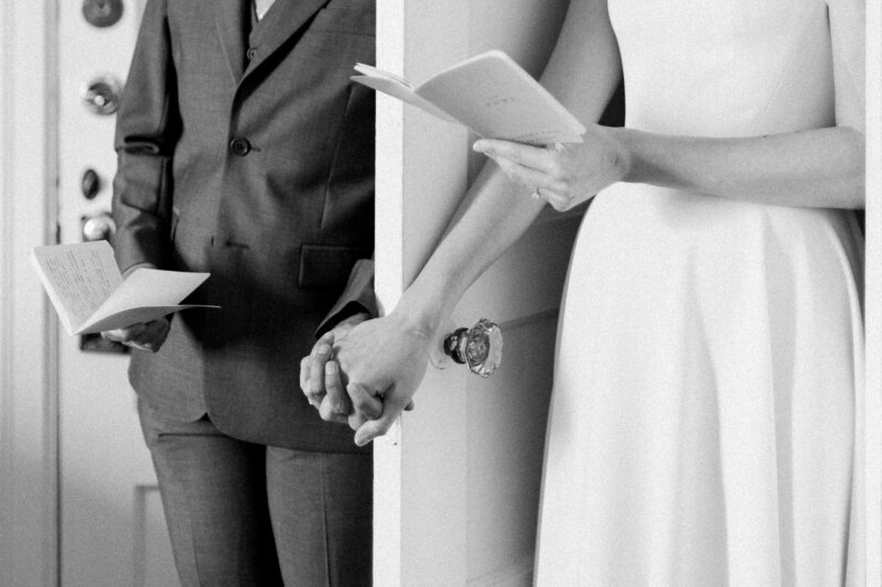 Close up of the hands of the two brides reading their private vows at the Peter Shields Inn suite