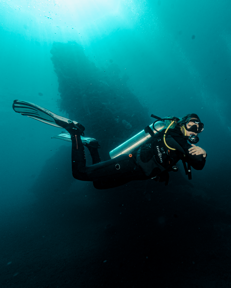 Perfect buoyance scuba diving girl with arms folded looking at camera in front of a sunken ship